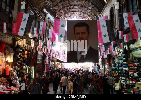 People walk under posters of Syria s presidential elections in Damascus, on May 25, 2014. Electoral campaigns in Syria started on May 11 and would end 24 hours ahead of the voting. (Xinhua/Bassem Tellawi) SYRIA-DAMASCUS-POLITICS-ELECTION PUBLICATIONxNOTxINxCHN   Celebrities Walk Under Posters of Syria S Presidential Elections in Damascus ON May 25 2014 Electoral Campaigns in Syria started ON May 11 and Would End 24 Hours Ahead of The Voting XINHUA Bassem  Syria Damascus POLITICS ELECTION PUBLICATIONxNOTxINxCHN Stock Photo