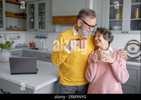 Happy senior couple drinking coffee or tea on home kitchen Stock Photo