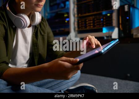 Teenager working at server, closeup view on hands using mobile tablet Stock Photo