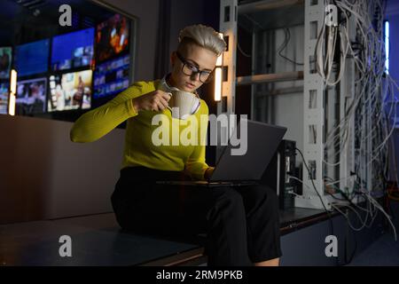 Young hipster woman working with laptop in server room Stock Photo