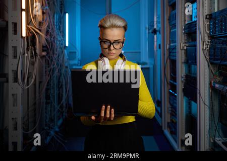 Portrait of concentrated woman programmer solving problem in data center Stock Photo