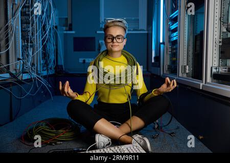Calm female IT technician meditating in server room Stock Photo