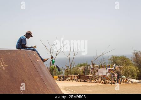 (140530) -- DAKAR, May 30, 2014 (Xinhua) -- A vendor waits for customers in front of his artworks stall at Ile de Goree in Dakar, capital of Senegal, May 24, 2014. The 11th edition of the Contemporary African Art Biennial, Dak Art, is being held in Senegal from May 9 to June 8. Dakar is located on the Cap-Vert Peninsula on the Atlantic coast. Its position, on the western edge of Africa, is an advantage for the integration of the contemporary African art into the international art market. (Xinhua/Li Jing) SENEGAL-DAKAR-CULTURE-ART PUBLICATIONxNOTxINxCHN   Dakar May 30 2014 XINHUA a Vendor Waits Stock Photo