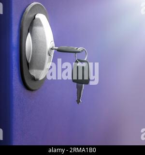 Key in keyhole on door. Inserting an key in a blue modern steal door with lock against illuminated background Stock Photo