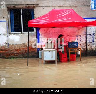 (140618) -- QUANZHOU, June 18, 2014 (Xinhua) -- A woman sells breakfast on a flooded road in Quanzhou County of Guilin City, south China s Guangxi Zhuang Autonomous Region, June 18, 2014. A rainstorm hit seven counties and cities of Guilin on Wednesday. (Xinhua/Liang Qian) (lfj) CHINA-GUANGXI-GUILIN-WATERLOGGING (CN) PUBLICATIONxNOTxINxCHN   Quanzhou June 18 2014 XINHUA a Woman sells Breakfast ON a flooded Road in Quanzhou County of Guilin City South China S Guangxi Zhuang Autonomous Region June 18 2014 a Rainstorm Hit Seven Counties and CITIES of Guilin ON Wednesday XINHUA Liang Qian  China G Stock Photo