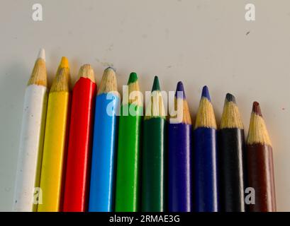 A photo of colouring pencils lined up beside each other on a white desk. Stock Photo