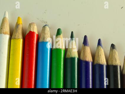 A photo of colouring pencils lined up beside each other on a white desk. Stock Photo