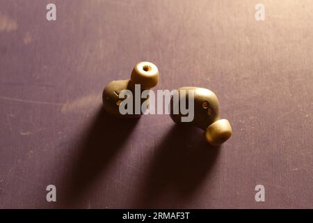 A photo of a two black earbuds in the light on a blue table. Stock Photo