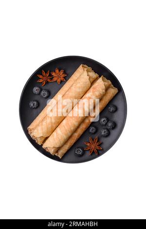 Delicious crispy wafer rolls with cream filling with nuts on a dark concrete background Stock Photo
