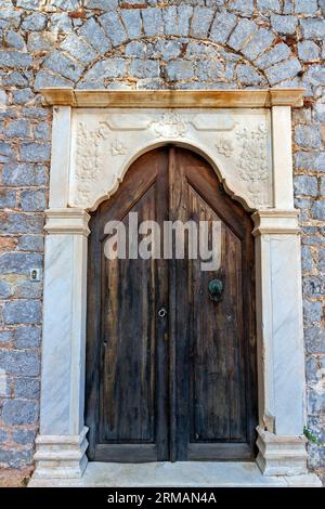Old wooden door of a mansion with decorated lintel, in Hydra town, Hydra island, Attica, Greece, Europe. Stock Photo