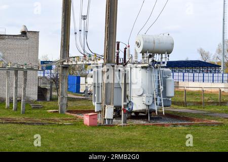 Large industrial iron metal transformer substation with transformers and high-voltage electrical equipment and wires with surge arresters to supply th Stock Photo