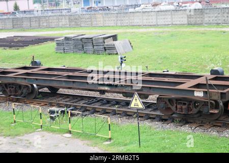 Rusty empty metal iron wheeled freight car for the train, locomotive for the carriage of goods along the rails at the railway station. Stock Photo