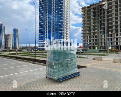 A large package of glass for windows of double-glazed windows wrapped with stretch film on the working site during the construction of houses. Stock Photo