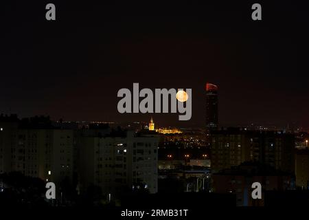 Night view of the city with the moon in the sky and buildings, Giralda and Pelli Tower, Seville, Spain Stock Photo