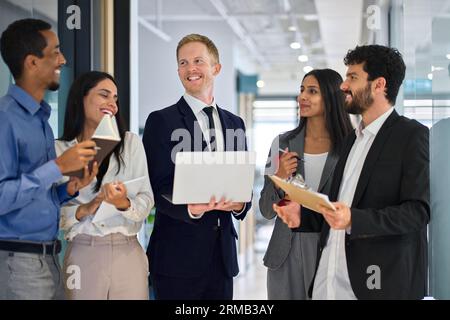 Happy international professional team business people talking in office hallway. Stock Photo