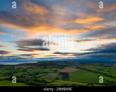 Shipton Gorge, Dorset, UK.  27th August 2023.  UK Weather.  The clouds glow orange at sunset above the fields around Shipton Gorge near Bridport in Dorset. Picture Credit: Graham Hunt/Alamy Live News Stock Photo