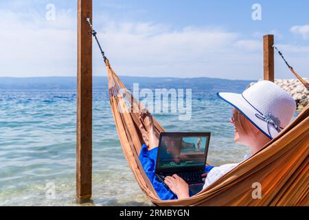 Video blogger, freelancer editing video at beach. Editing Videos On Laptop Using Video Editor App. Stock Photo