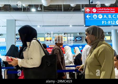 Female tourists arriving at Dubai airport - connected flights, signs. Dubai airport arrivals interior Stock Photo