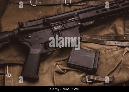 Modern automatic carbine and backpack on a wooden table. A set of fighter ready for any battle conditions. Stock Photo