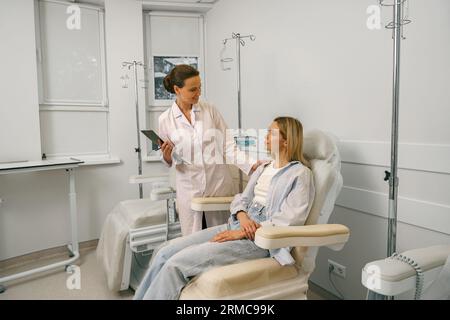 Nurse or doctor talking with patient while preparing her for infusion drip in hospital  Stock Photo