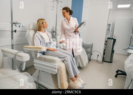 Nurse or doctor talking with patient while preparing her for infusion drip in hospital  Stock Photo
