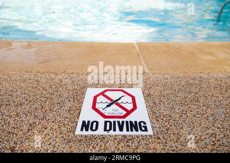 Edge of swimming pool with NO DIVING warning sign. Stock Photo