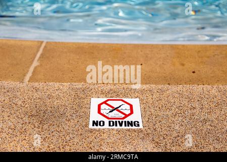 Edge of swimming pool with no diving warning sign Stock Photo