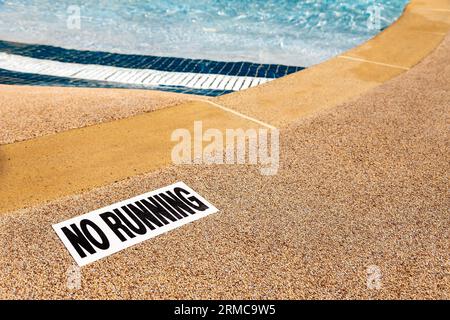Edge of swimming pool with NO RUNNING warning sign. Stock Photo