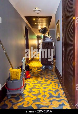 Housekeeping cart in a hotel corridor. Cleaning hospitality housekeeper's trolley beside a room entrance Stock Photo