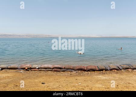 Tourists covered in mud swim in Dead Sea, Jordan Stock Photo