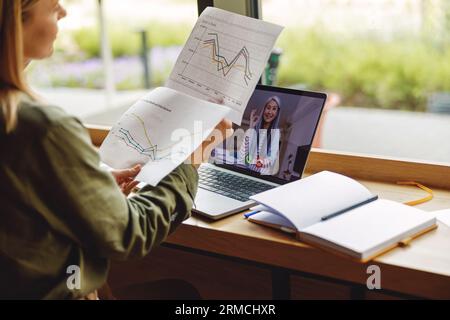 Close up of woman analyst working with documents during videoconference sittingin near window Stock Photo