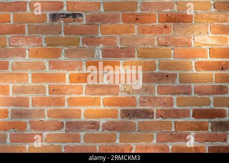 Full frame texture background of an old 19th century red and brown exterior brick wall with faint tree shadows cast upon it. Stock Photo