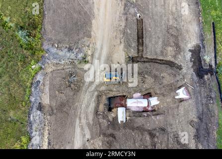 Dozer next to an open trench with two culverts ready for a connection juncture.  Stock Photo
