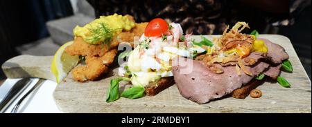 A selection of Smørrebrød served on a wooden cutting board. Copenhagen, Denmark. Stock Photo