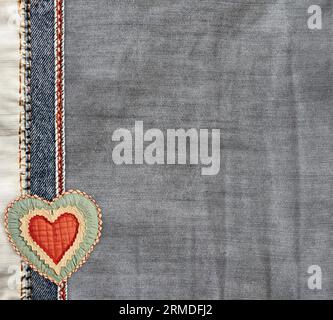 Grey and light grey  denim background with a seam and felt heart. Light gray color denim jeans fabric texture. Valentine's day denim backdrop. Copy sp Stock Photo