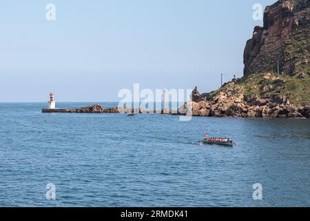 PASAIA, SPAIN-JULY 10, 2023: People canoeing at the entrance to the Bay of Pasaia. Ocean bay, sunny. Stock Photo