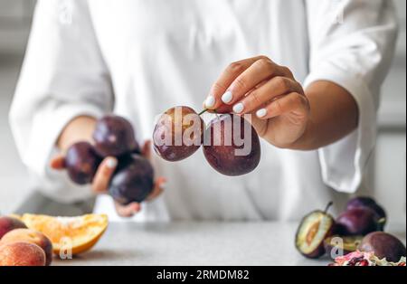Plums in the hands of a woman in the kitchen. Stock Photo