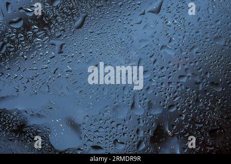 Raindrops on a clear window create a wet and rainy background. Stock Photo