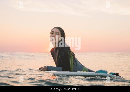 surfer girl posing in the water sunset Stock Photo