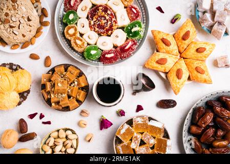 Middle Eastern Sweets, Turkish Delights and Black Coffee on white background. Arab dessert assortment, rahat lokum, halva, sherber, pismaniye with nut Stock Photo