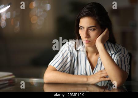 Sad pensive woman looking away alone at home in the night Stock Photo