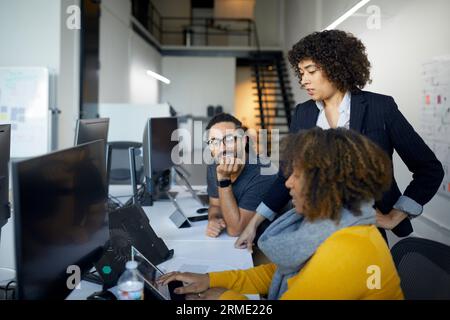 Coworkers discussing over tablet computer on desk in office Stock Photo