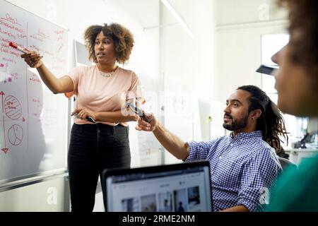 Colleagues pointing while discussing business plan in meeting at office Stock Photo