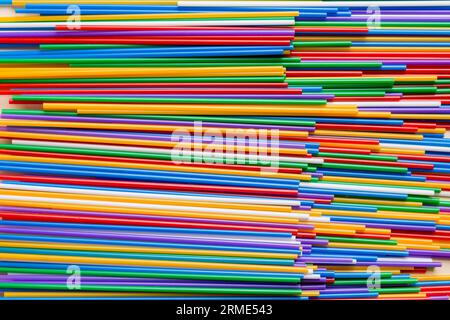 many multi-colored plastic tubes for cocktail on Colored background, top view. Stock Photo