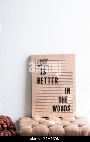 A 'Life is Better in the Woods' Sign sitting on a brown leather Stock Photo