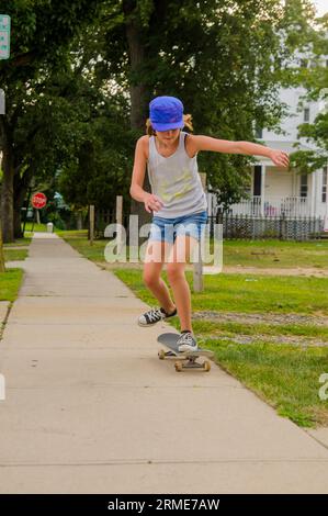 Skater girl doing tricks on sidewalk Stock Photo