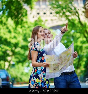 Couple of tourists using map and looking for the direction near the Eiffel tower in Paris Stock Photo