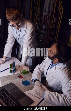 multiethnic scientists working near test tubes, petri dishes and laptop in innovative laboratory Stock Photo