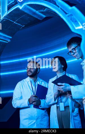 futuristic research, multiethnic scientists examining experimental device in innovation hub Stock Photo