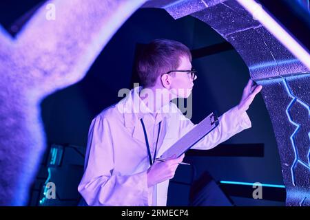 future technologies, young intern with clipboard examining new equipment in science center Stock Photo